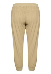 Beige elastische taillebroek met geplooide boorden, gemaakt van lichte stof. Heeft een subtiele textuur en twee zijzakken.