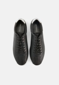 Μαύρα δερμάτινα αθλητικά παπούτσια με ομαλή υφή, στρογγυλεμένη μύτη και σχέδιο με κορδόνια. Διαθέτουν διακριτικές λεπτομέρειες ραφής και λευκή λεπτομέρεια στη φτέρνα.