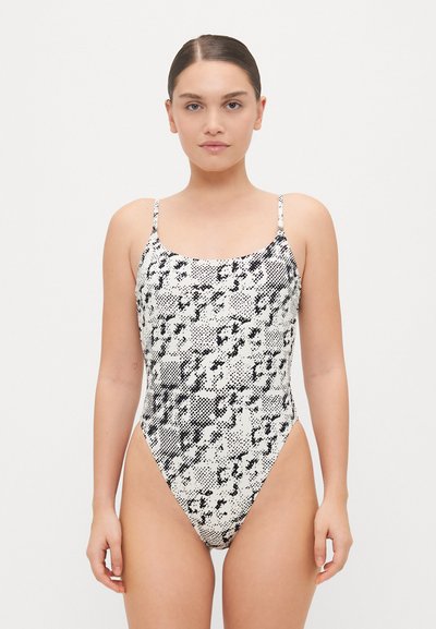 Black and white snakeskin-patterned one-piece swimsuit with thin straps and a high-cut leg design, made of smooth, stretchy material.