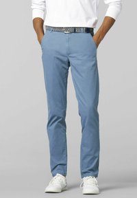 Chinos azzurri chiari realizzati in un tessuto texturizzato, con tasche laterali, una cintura con un design a fantasia e abbinati a sneaker bianche.