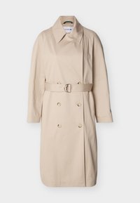 Μπεζ διπλής κουμπώματος παλτό με φαρδιά γιακά, μακριά μανίκια, ζώνη με ασημένια αγκράφα στη μέση και κουμπιά μπροστά.
