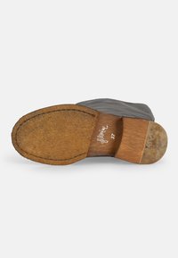 Suela de cuero marrón con acabado texturizado, tacón de madera y grabado de la marca "filozai". El zapato tiene un diseño elegante y minimalista.
