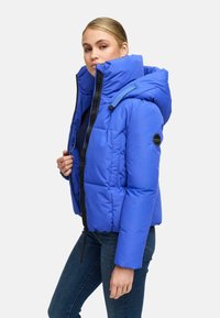 Blauwe pufferjack met hoge kraag, ritssluiting en zwarte accenten. Kenmerkt zich door een dikke, doorgestikte ontwerp en zijzakken. Zachte textuur.