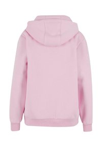 Šviesiai rožinė sportinė gobtuvė su priekiniais kengūriniais kišenėmis, raišteliu reguliuojamu gobtuvu ir veliūrinėmis rankogaliais bei apačia. Minkšta audinio medžiaga su lygiu paviršiumi. Vaizdas iš nugaros.