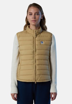 Gilet imbottito beige con cuciture verticali, colletto alto e zip frontale. Logo evidente sul lato sinistro del petto. Maniche bianche strutturate contrastano con il gilet.