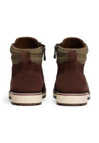 Stivaletti in suede marrone con collare in tessuto verde, zip laterali e suole in gomma crema con righe rosse e blu.
