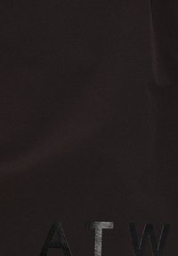 Tissu noir avec de grandes lettres noires brillantes « A T W » imprimées près du bord inférieur.