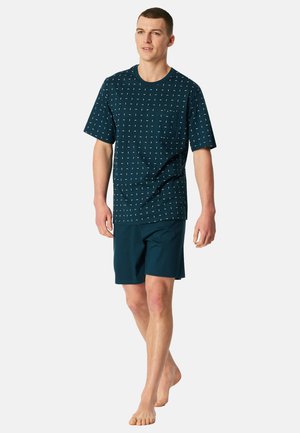 T-shirt blu navy con fantasia e taschino, abbinata a pantaloncini blu navy tinta unita. Tessuto morbido, vestibilità rilassata e rifiniture con orlo semplice.