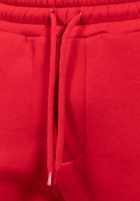 Röda sweatpants med en mjuk textur, elastisk midja och dragsko-detalj. Ena sidan har en diskret ficka för nytta.