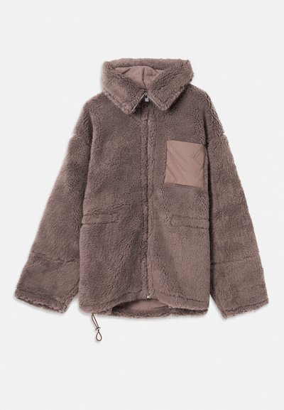 Brūna, pūkaina fļēsu jaka ar apkakles kaklu, ar rāvējslādzi, divām priekšējām kabatām un gaišāku brūnu kabatas detaļu.