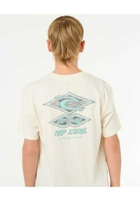 Kremowa koszulka z krótkim rękawem z niebieskim wzorem graficznym z tyłu, z napisem "RIP CURL" i abstrakcyjnymi motywami fal.