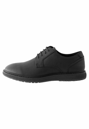 Zapato de vestir de cuero negro con punta redondeada, diseño de cordones de seis ojales, parte superior texturizada y suela de goma plana.