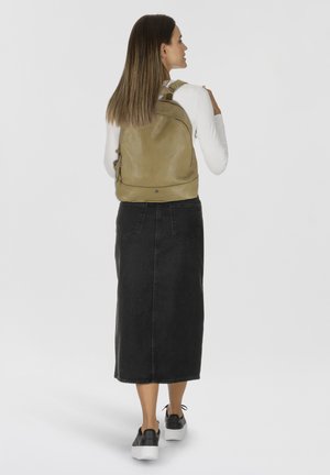 Zaino in pelle verde con una superficie liscia e design curvo, dotato di spallacci regolabili e una tasca con zip sul lato.