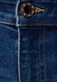 Donkerblauwe denim met zichtbare textuur. Bevat een metalen knop met een zwarte kern omringd door heldere rhinestones en contrasterende stiksels.