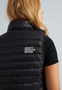 Schwarze Daunenweste mit gestepptem Design, hochabschließendem Kragen und roten Akzenten. Auf der Rückseite steht in weißem Text "JACK1T SATELITE DES1GN."