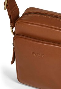 Brun läder axelväska med en dragkedjestängning, med en framficka och ett robust rem. Varumärket "HOWARD" är präglat på framsidan.