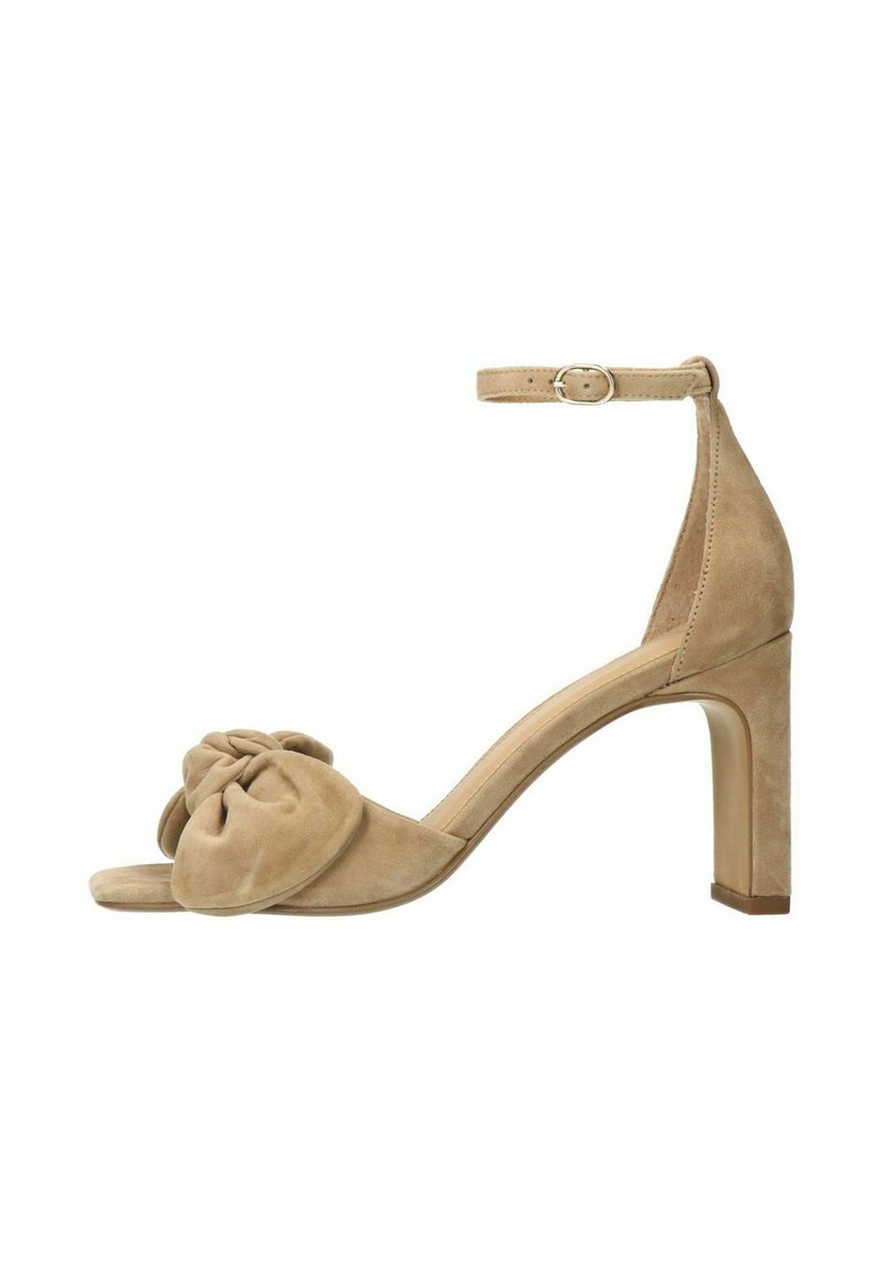 Beige suede enkelhoge sandaal met een open teen, enkelbandje en een geknoopt stofdetail aan de voorkant. Blokhak voor stabiliteit.