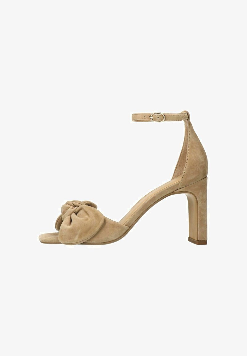 Beige suede enkelhoge sandaal met een open teen, enkelbandje en een geknoopt stofdetail aan de voorkant. Blokhak voor stabiliteit.
