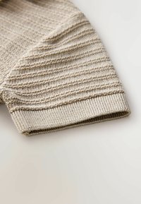 Pleteni bež kos s horizontalnimi črtami, rebrastim manšetom in mehko teksturo. Rob je lepo obdelan za vzdržljivost.