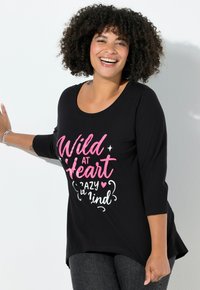 Černé tričko s dlouhým rukávem s růžovým a bílým nápisem "Wild at Heart Crazy in Mind." Hladká látka, zaoblený lem.