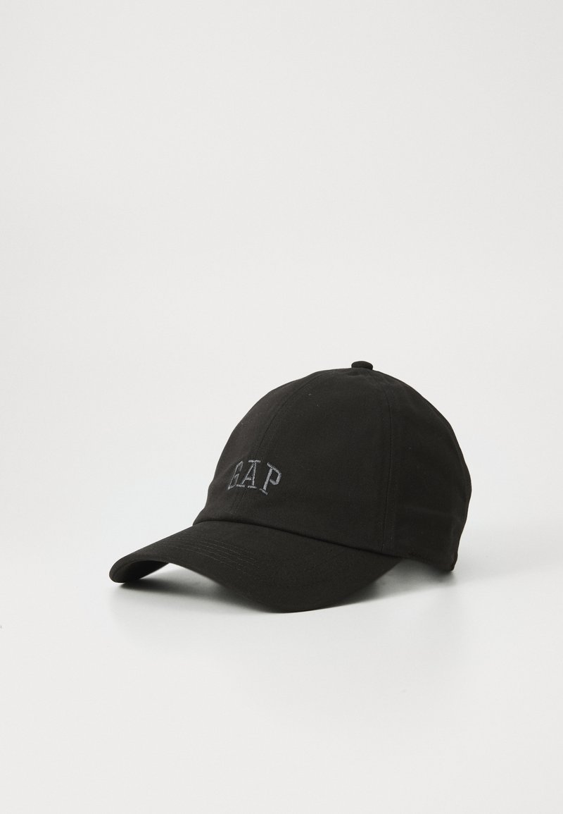 Casquette de baseball noire avec une visière incurvée et un logo brodé "GAP" à l'avant, placée sur une surface blanche.