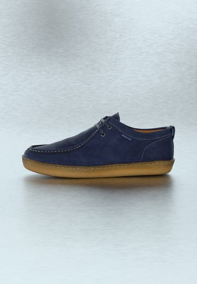 Καθημερινό παπούτσι από σουέντ σε ναυτικό μπλε με καφέ λαστιχένια σόλα, σχεδιασμό με κορδόνια και ορατά ράμματα, σε γκρι ανακλαστική επιφάνεια.