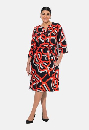 Schwarzes Kleid mit mutigen roten und weißen geometrischen Mustern, das eine taillierte Taille, Dreiviertelärmel und einen knielangen Saum aufweist.