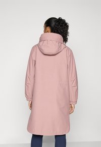 Lang rosa frakk med hette, med elastiske mansjetter og sidelommer. Glatt tekstur og minimalistisk design.