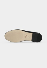 Semelle d'une chaussure plate en cuir noir avec un avant beige texturé, un talon noir et la marque BOSS avec la taille 37 imprimée sur la semelle.