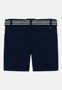 Shorts bleu marine avec deux poches arrière et une ceinture rayée blanche et bleue marine passée dans des passants.