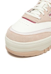 Svijetloružičasta tenisica s bijelom kožnom prednjom stranom, teksturiranim bočnim stranama od ružičastog antilopa te debelim gumeniim potplatom s uzorkom za bolje prianjanje.