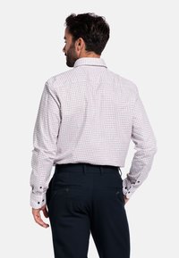 Wit geruit overhemd met lange mouwen, met blauwe en rode ruitpatronen, een opstaande kraag en zwarte knopen. In combinatie met donkere broeken.