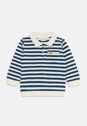 Småbarns langermet polo skjorte med marineblå og hvite horisontale striper, kremfarget krage og mansjetter, to knapper og en stripete brystlomme.