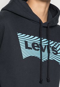 Zwarte hoodie van katoen met een blauw gestreept Levi's-logo. Het ontwerp heeft verstelbare koordjes en een gestructureerde stof.