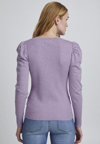 Maglione rib ribbed viola con maniche lunghe e aderenti, dettaglio sulle spalle arricciato e scollatura rotonda. Abbinato a jeans in denim.