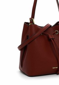 Rode lederen emmer tas met een gestructureerde afwerking, voorzien van een trekkoordsluiting, een verstelbare schouderband en een goudkleurig logo detail.