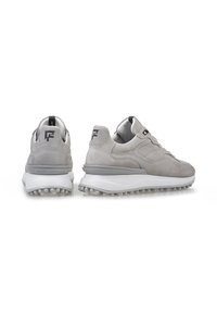Zapatillas de ante gris con suela de goma blanca, que presentan un diseño en capas y acentos texturizados. Marca presente en el talón y la lengüeta.