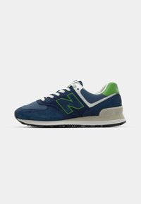 Navy suede sneakers with a green logo, white accents, and a gray midsole. Features a lace-up design and a textured rubber outsole.