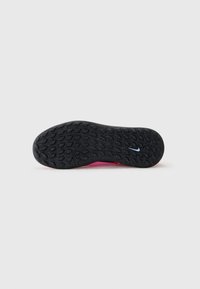 Nike shoe sole with a textured black rubber surface, featuring a pink heel section and a small blue swoosh design.