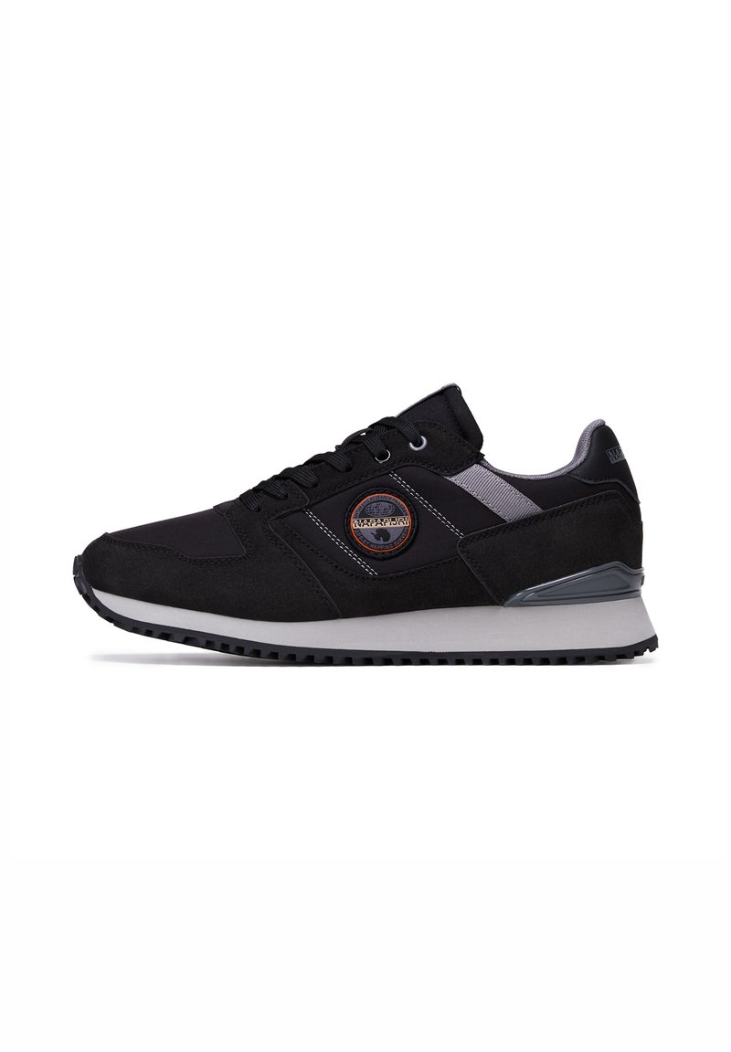 Sneaker nera con un mix di texture liscia e scamosciata, suola grigia ammortizzata, dettagli riflettenti e un'etichetta con logo sul lato.