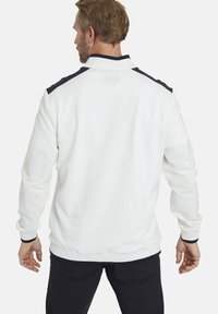 White, textured jacket with a high collar, navy accents on shoulders, ribbed cuffs, and hem. Back view shows clean lines and fitted design.