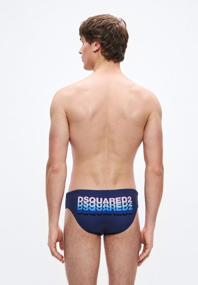 Calções de banho de cor azul-marinho com o logótipo "DSQUARED2" em texto degradé azul e rosa, concebidos com um ajuste justo e textura suave.