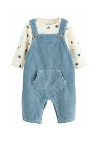 Blue corduroy overall with a front pocket and wooden buttons, layered over a cream long-sleeve shirt with a geometric pattern in pastel colors.