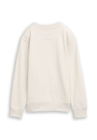 Sudadera de color crema, con cuello y puños acanalados, textura de tela suave y un detalle de parche rectangular en la parte posterior.