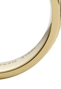 Bague en acier inoxydable de ton or, avec une surface lisse ornée d'un délicat motif gravé et d'un logo à l'intérieur de l'anneau.