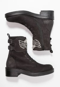 Botines de ante negros con acentos decorativos de strass, frente con cordones, cremalleras laterales y tacones cuadrados. Cuenta con correas dobles con hebillas.