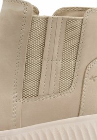 Bēšveida zābaki ar teksturētu auduma paneli, gludu ādas akcentu un smalku šuvju detaļām sānos un ap zoli.