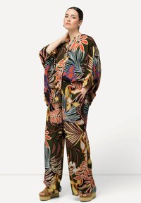 Blomsterprint to-delt sæt bestående af en løs, åben front top og brede bukser i jordnære farver som grøn, orange og lilla. Inkluderer platform sandaler.