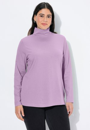 Fioletowa bluzka z długim rękawem i golfem, wykonana z gładkiego materiału, o luźnym kroju. Posiada wysoki kołnierz i zaokrąglony dół, zestawiona z ciemnymi spodniami.