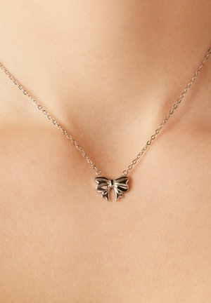 Zilveren ketting met een strikvormige hanger, met een gepolijste oppervlakte, fijne ketting en delicate details. Verstelbare lengte.